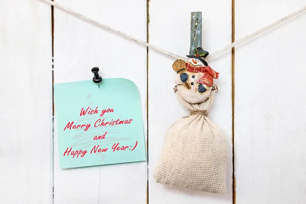 Snowman clothespin holding sack and Christmas greeting note — Stock Photo, Image