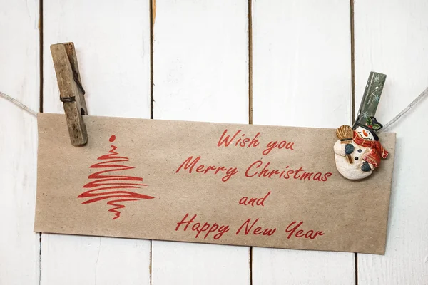 Christmas snowman clothespins holding greeting card — Stock Photo, Image