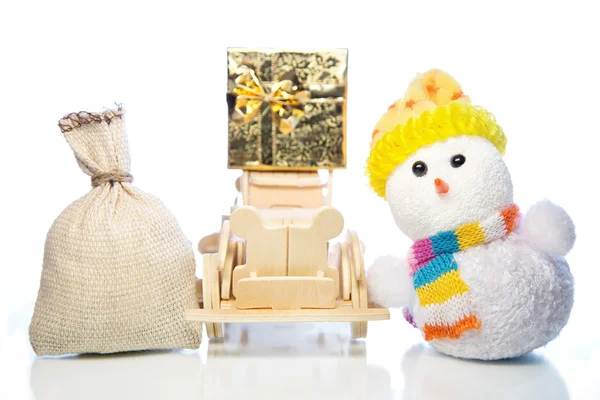 Snowman with wooden car, gift box and sack — Stock Photo, Image
