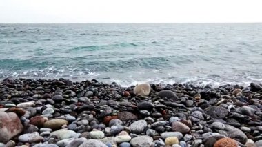 Dalgalar sahilinin plaj veya okyanus ya da deniz kıyısında taşlarla