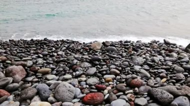 Dalgalar sahilinin plaj veya okyanus ya da deniz kıyısında taşlarla