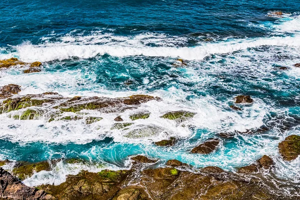 Piedras en olas con espuma en la costa —  Fotos de Stock