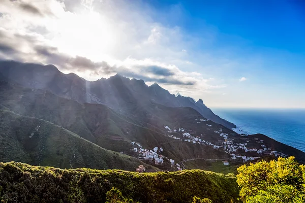 Montanhas com nuvens e sol sobre pequena aldeia — Fotografia de Stock