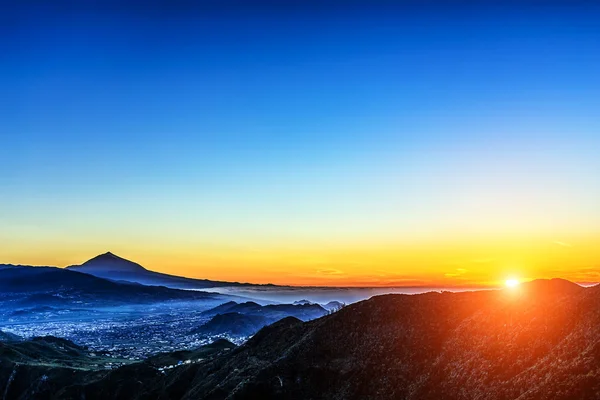 Sole sopra montagne su cielo azzurro con nebbia — Foto Stock