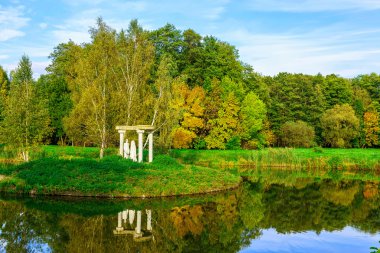 Sonbahar Doğa Göl tarafından heykeller, renkli ağaçlar, yeşil çim ile