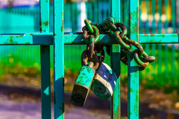 Металлический забор с ржавым замком и цепью
