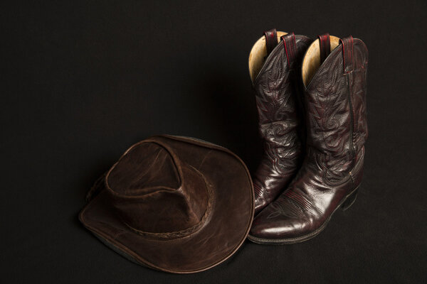 Cowboy boots and cowboy hat on black background