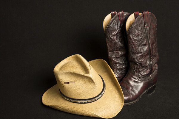 Cowboy boots and cowboy hat on black background