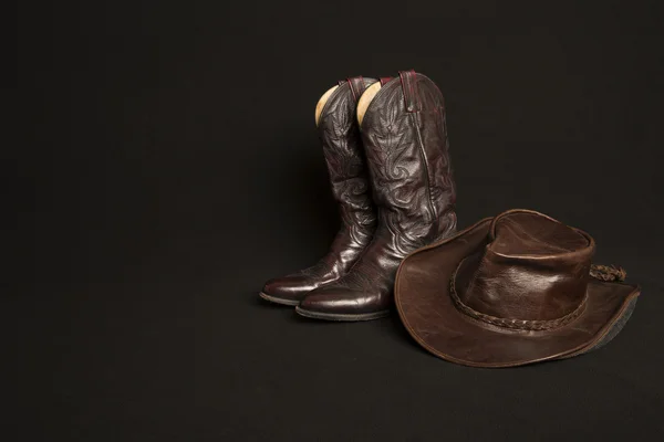 Kovboy çizmeleri ve kovboy şapkası siyah arka plan üzerine