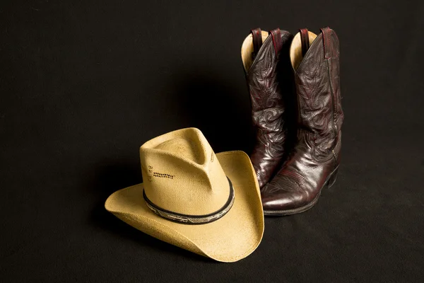 Kovbojské boty a klobouk na černém pozadí Royalty Free Stock Fotografie