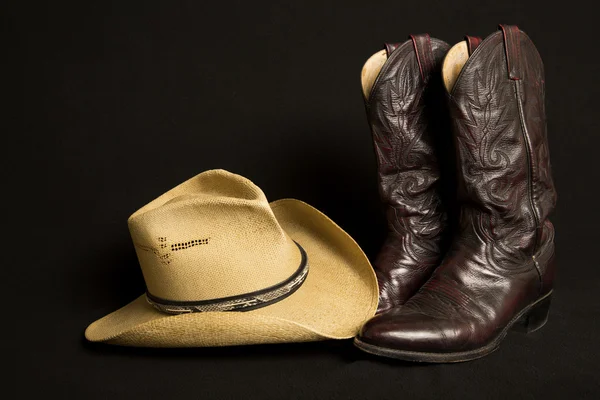 Kovbojské boty a klobouk na černém pozadí Royalty Free Stock Fotografie