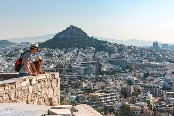 Dos turistas miran el panorama de Atenas y de las paredes del fro de la colina del Licabetus de Acropolis . — Foto de Stock