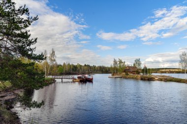 Wooden summerhouse on small island and sailing boats near small pier at river Daugava, Latvia