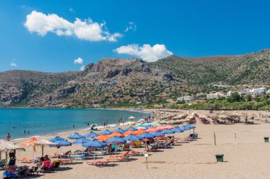 Şezlong ve sunny beach Palaiochora Crete adada turist.