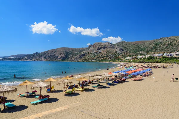 Lehátka a turisté na slunné pláži Palaiochóra na ostrově Kréta. — Stock fotografie