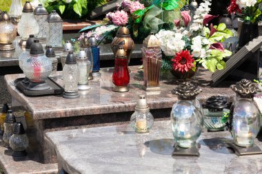 Mumlar, bir sürü adak ışığı ve çiçek, yakın çekimde dekorasyon. Mezarlıktaki ışıklar yakın çekim, ölüm, hafıza, geçiş, basit kültürel sembolü hatırlamak, kavramsal çekim, hiç kimse