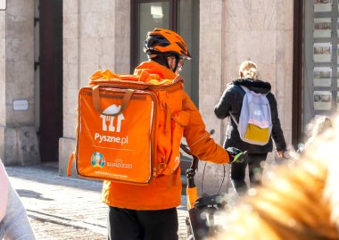 Sadece Takviye Pyszne.pl ye, fast food teslimatçısı, Pyszne portakal rengi sırt çantalı bisiklet sürücüsü, arkasında logo olan, arkadan çekilen