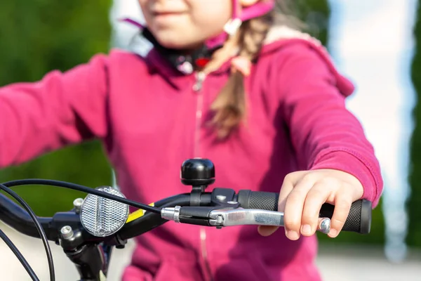 Little child, young school age cyclist riding a bike pressing the brake holding the handle bars, hands closeup. Kid sitting on a bicycle using the handbrake, braking and stopping, leisure, lifestyle