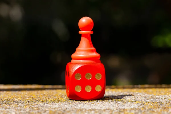 Winning, success simple abstract concept, single red toy game piece, chess pawn standing on the red board game dice showing six. Lucky throw, podium, winner, successful player conceptual, nobody