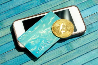 Bitcoin altın sikke ve hediye kartı, modern bir akıllı telefon ekranının üstünde duran kredi kartı. BTC engelleme zinciri ödemeleri, taşınabilir depolama ve ödeme, kripto para birimi soyut kavramı ile ödeme