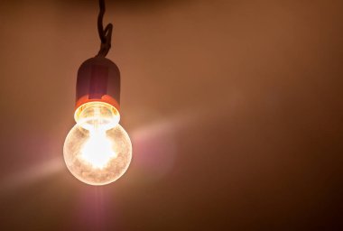 Karanlık bir odada tek bir parlak parlak parlak parlak ampul, nesne detayı, yakın plan, parlak sarı ışık kaynağı odayı aydınlatıyor, karanlık soyut kavramda ışık, hiç kimse