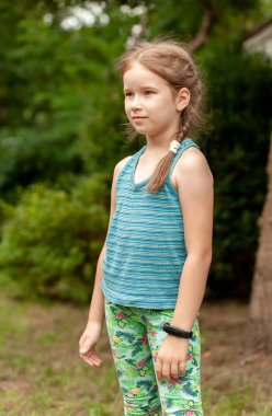 Kendine güveni tam bir okul çağında gülümseyen mutlu bir çocuk dışarıda fitness bandı takıyor, akıllı saat takıyor, dik duruyor, dikey açık havada çocuklar ve teknoloji konsepti, yaşam tarzı...