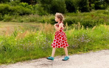 Küçük bir çocuk yürüyor, yeşil bir arazide geziniyor, kırsal alanda yürüyor, okul çağındaki kız tek başına dolaşıyor, kopyalama alanı. Serene açık hava sahnesi, çocuklar sağlıklı aktif yaşam tarzı konsepti