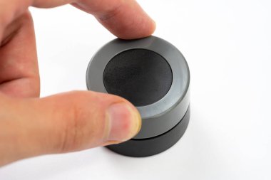 Adam parmaklarıyla basit bir yuvarlak gri düğmeyi ayarlıyor, beyaz arkaplanda izole edilmiş nesne, elektronik ayarlar için döner kontrol kadranı, düğmeyi çeviren elin yakın çekimi, elektronik cihaz.
