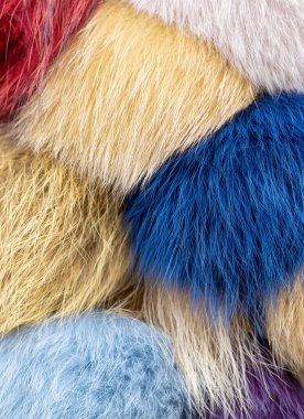 Çok renkli sahte kürk topları kapanıyor, kabarık tüylü tekstil dokusu kırmızı mavi bej ipliklerle, yumuşak pelüş malzeme dikey karargah arka planı soyut sıcak yüzey ayrıntıları, insan yok.