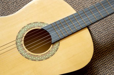 Akustik klasik gitar, fretboard 'un ses deliğini ve dekoratif roketi geçmesiyle, yerde yatarken, sıcak renkli ahşap vücut ve teller ayrıntılı müzik enstrümanı hala yatay