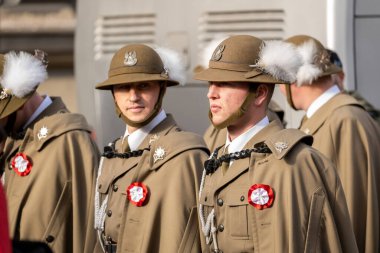 Polonyalı askerler tören üniformaları içinde tüylü askeri şapkalar, 11 Kasım 'daki Bağımsızlık Günü geçit töreninde kırmızı beyaz rozetler, dışarıda onur kıtası ayakta duruyor, ayrıntıları kapatın.