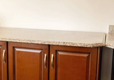 Granit yüzeyi ve ahşap dolap kapıları olan boş mutfak tezgahı, ürün gösterimi için geniş bir fotokopi alanı olan ön açı iç plan, nesne olmadan en az ev sayacı çalışma alanı