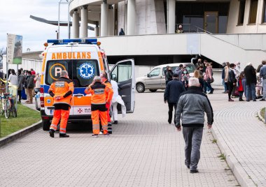 Polonya 'nın Krakow Lagiewniki kentindeki hac alanında açık kapısı olan tıbbi kurtarma ekibi ve ambulans minibüsü yüz maskesi takan ziyaretçi kalabalığı, acil sağlık desteği, kamu güvenliği, toplu toplantı.