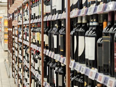 Süpermarkette şarap reyonu, raflarda sıradan şişelenmemiş kırmızı şarap, etiketli geniş perakende perakende perakende satış, alkol bölümü konsepti, geniş seçim, insan yok.