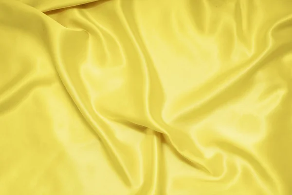 Yellow texture of silk, satin. Shiny fabric background.