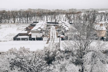 Karla kaplı evlerin, ağaçların ve arabaların penceresinden bak.