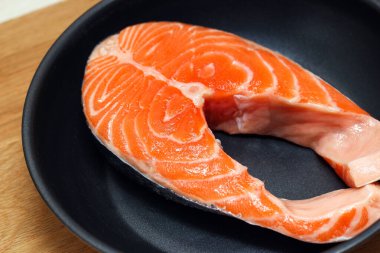 Siyah tavada taze somon bifteği. Yemek pişirmeye hazırlanıyor..