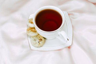 Çay fincanı çay, çay tabağı, kurutulmuş hurma tatlısı ve ipek masa örtüsü..