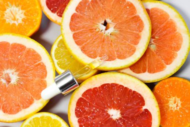 Beyaz arka planda farklı narenciye meyveli C vitamini içeren yüz serumu..
