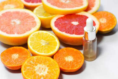 Beyaz arka planda farklı narenciye meyveli C vitamini içeren yüz serumu..