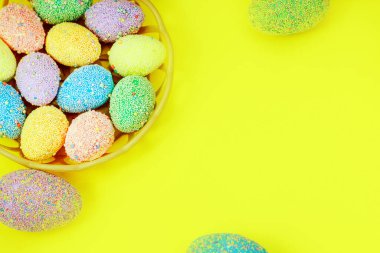 Sarı arka planda bir sepette çok renkli Paskalya yumurtaları. Boşluk metnini kopyala
