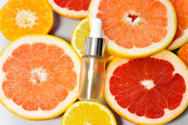 Beyaz arka planda farklı narenciye meyveli C vitamini içeren yüz serumu..