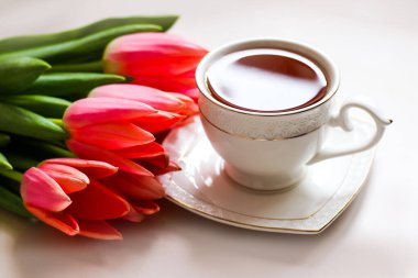 Bir fincan çay ve bir buket pembe lale. Kahvaltı kompozisyonu minimalizmi. Bahar konsepti.