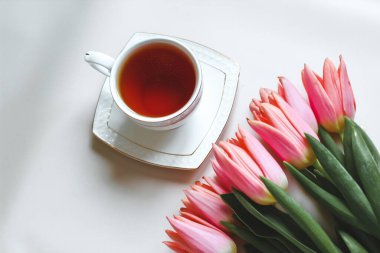 Bir fincan çay ve bir buket pembe lale. Kahvaltı kompozisyonu minimalizmi. Bahar konsepti.