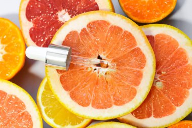Beyaz arka planda farklı narenciye meyveli C vitamini içeren yüz serumu..