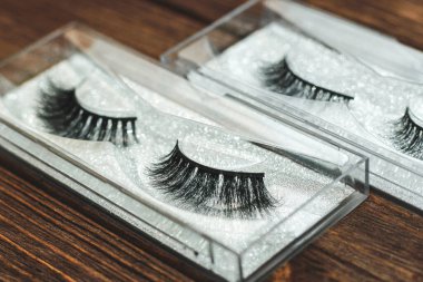 Ahşap bir arka planda sahte kirpikler. Göz kapakları için makyaj..