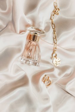 Kadın mücevherleri, altın zincir, modaya uygun mücevherler, ipek arka planda parfüm..