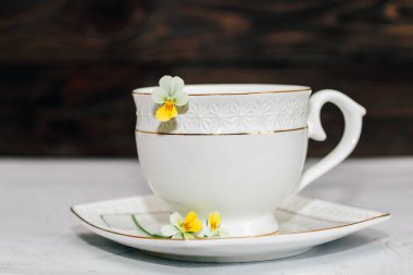 Çiçeklerle süslenmiş altın kenarlı güzel beyaz bir kupa. İş hesabı tasarımı.