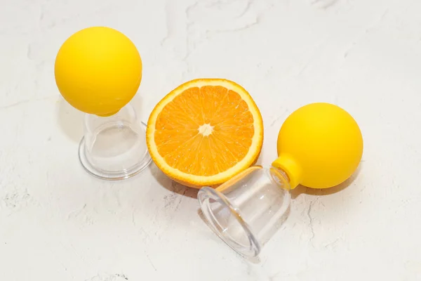 Vacuum massage anti-cellulite cups on a gray background with an orange. Self-massage for healthy skin.