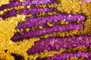 Pulların parlak dokusu renk değiştiriyor. Mor ve sarı. Süslü elbiseler için kumaş.